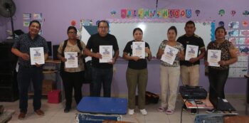 River Ministry missionary Pedro Muñoz poses with a group of parents holding Family Health Parenting Program manuals in a classroom