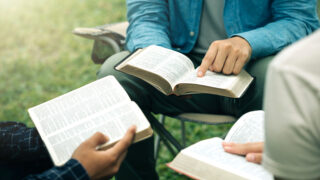 Christian group read and studied the bible at the park and prayed together. sharing the gospel with a friend. Holy Bible study reading together on Sunday. Study the Word Of God With Friends. Education