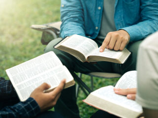 Christian group read and studied the bible at the park and prayed together. sharing the gospel with a friend. Holy Bible study reading together on Sunday. Study the Word Of God With Friends. Education